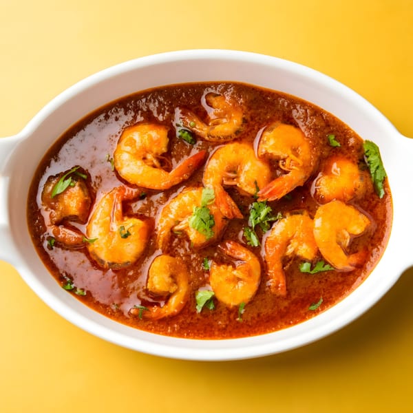 Spice Affair's Indian shrimp curry, garnished with fresh cilantro, served in a white oval dish.