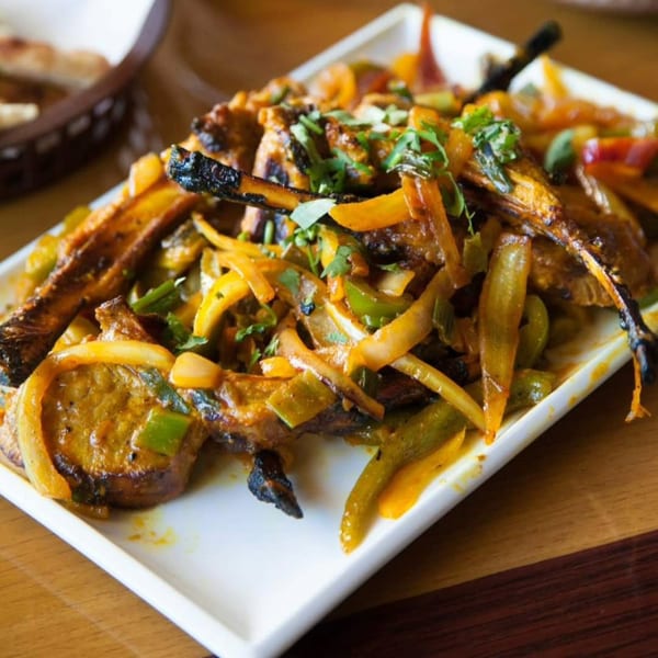 Spice Affair's Indian dish with grilled vegetables, meat, and fresh herbs on a white plate.